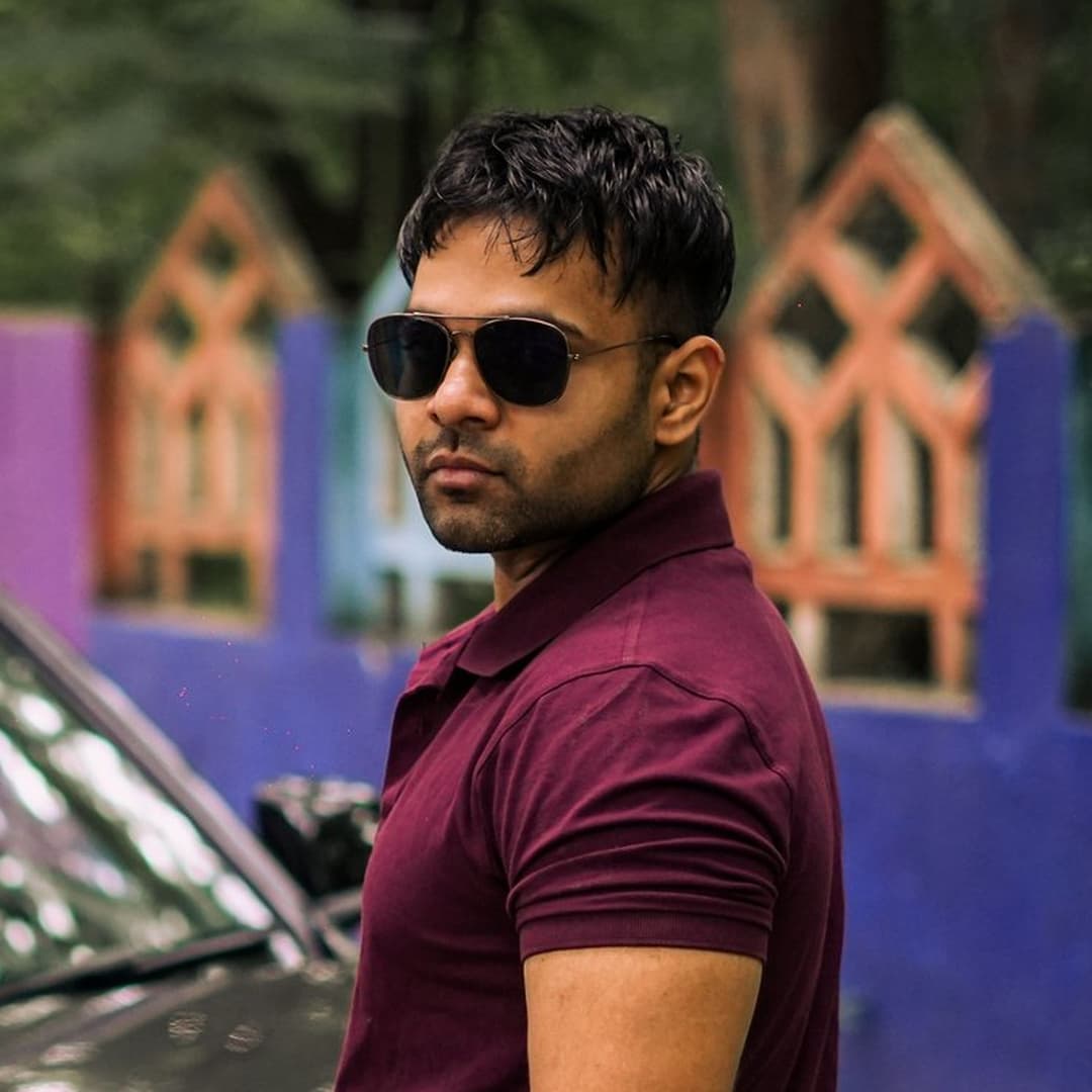 Existing real source portrait of Abhay Rohit in a burgundy shirt and sunglasses against an out-of-focus outdoor background.